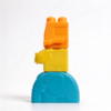Stacking blocks set in orange, yellow and blue, a molded stud block stacked on an animal body on a white background
