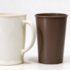 Promotional plastic cup pair, with a cream handled mug beside a brown tumbler on a white background