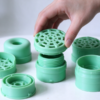 Filter cover assembly in green, a hand setting the mesh cap down onto the threaded base