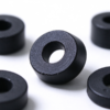 Molded plastic spacer standing on edge in black, showing the center bore and the matte molded outer wall