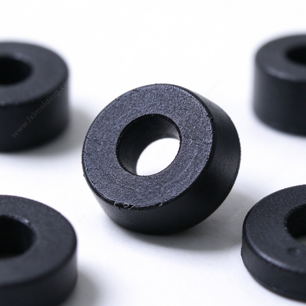 Molded plastic spacer standing on edge in black, showing the center bore and the matte molded outer wall