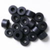 Molded plastic spacer rings in black, a pile of rings with center bores and small holes around the bore