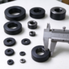 Molded plastic spacer rings in several outer diameters on a bench, a caliper laid across one ring