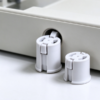 Push-in snap bushing pressed into a hole in a white panel wall, with a second part beside it
