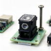 Optical sensor housing shown on a green circuit board with a long screw beside it, a board mount part in black