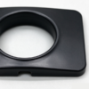 Plastic cover plate in black up close, the round collar proud of the face around the bore and the notch in the edge