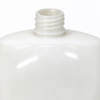 Cosmetic bottle in white up close, the threaded neck standing under the rounded shoulder