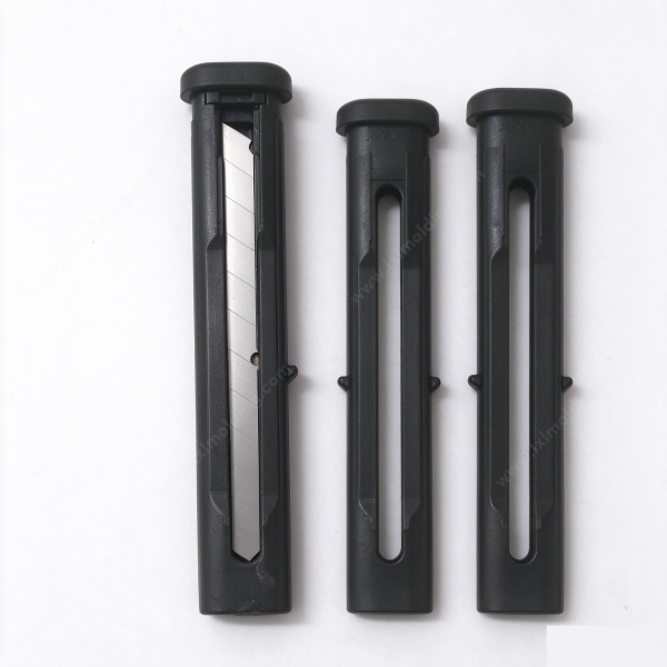 Utility knife housing in black, one sleeve open with a utility blade inside and two empty sleeves beside it